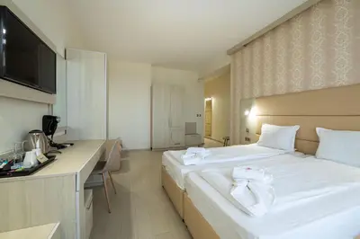a hotel room with a large white bed and a desk at Perla Apartments First Line in Nesebar