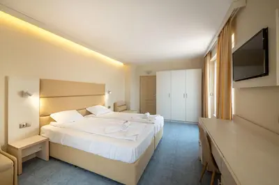 a hotel room with two beds and a flat screen tv at Perla Apartments First Line in Nesebar