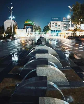 a fountain in a parking lot at night at ART LUXURY Apartment in Burgas City