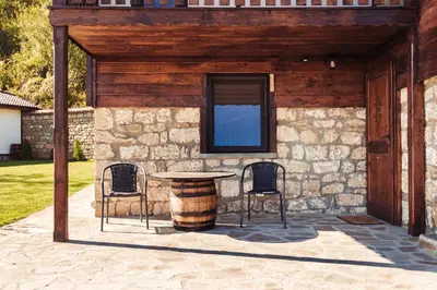a patio with a table and chairs and a building at Guest House Hristova Kashta - Христова Къща in Cherni Vrŭkh