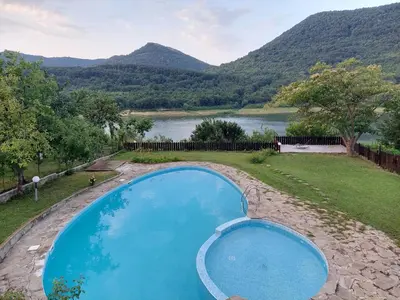 a swimming pool with a view of a river and mountains at СЪНТОВЕЦ - на брега на язовир Цонево in Tschenge