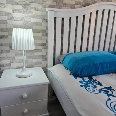 a bedroom with a bed with a nightstand and a lamp at Aпартамент 5 in Varna City