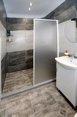 a bathroom with a shower with a sink and a mirror at Lux Apartment 