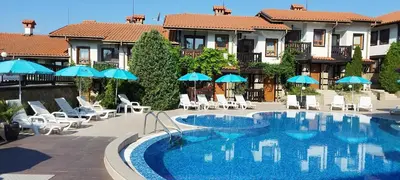 a large swimming pool with chairs and umbrellas at Pearl Apartments Sozopol in Sozopol