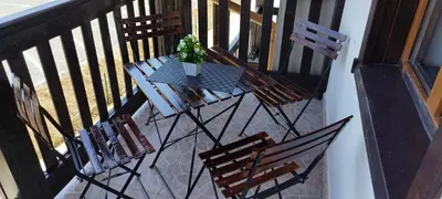 a table with chairs and a potted plant on a balcony at Pearl Apartments Sozopol in Sozopol