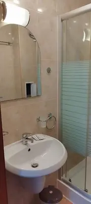 a bathroom with a white sink and a shower at Pearl Apartments Sozopol in Sozopol