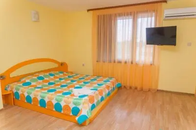 a bedroom with a bed and a flat screen tv at Къща за гости КАТИ in Kiten