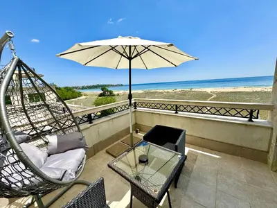 a balcony with a swing and a table and an umbrella at Teos Apartments Primorsko in Primorsko