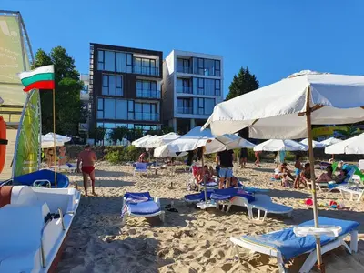 a beach with chairs and umbrellas and people on it at Апартамент За Гости ,,ХРИСТИНА