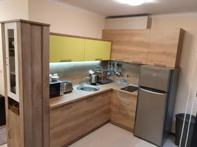 a kitchen with wooden cabinets and a stainless steel refrigerator at Апартамент За Гости ,,ХРИСТИНА
