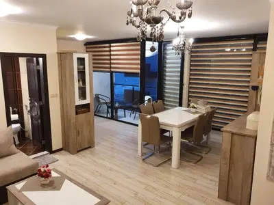 a dining room and living room with a table and chairs at Апартамент За Гости ,,ХРИСТИНА