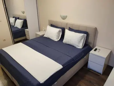 a bedroom with a blue and white bed and a mirror at Апартамент За Гости ,,ХРИСТИНА