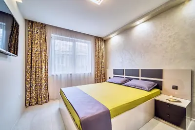 a bedroom with a large bed and a window at Апартамент S Apart in Varna City