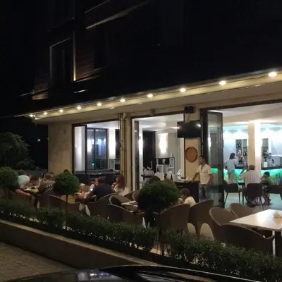 a group of people sitting at a restaurant at night at Apartments Stamopolu Lux with pool view in Primorsko