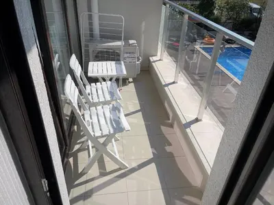 a balcony with two white chairs on a patio at Apartments Stamopolu Lux with pool view in Primorsko
