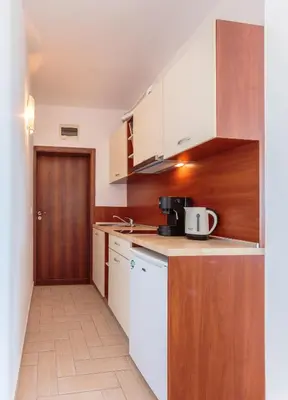 a small kitchen with white appliances and a wooden door at Via Pontica 123 Guest Apartments in Sozopol