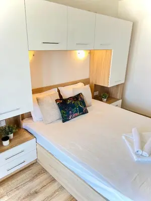 a bedroom with a large white bed with white cabinets at Summer Apart Janet in Obzor