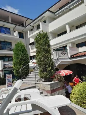 a building with white lounge chairs and an umbrella at ЛЕСО-Зара студио in Ravda