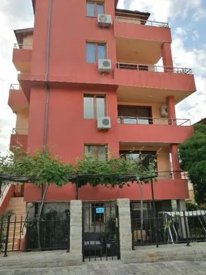 a red building with trees in front of it at Дом Апостолови in Sozopol