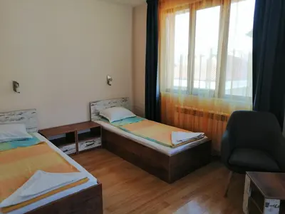 a bedroom with two beds and a chair and a window at Дом Апостолови in Sozopol