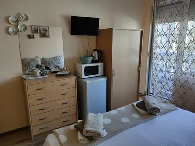 a bedroom with a bed and a microwave and a dresser at Самостоятелни стаи Виктория in Pomorie