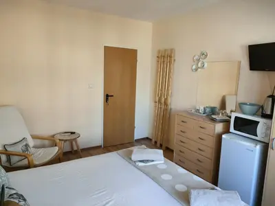 a bedroom with a bed and a microwave and a refrigerator at Самостоятелни стаи Виктория in Pomorie