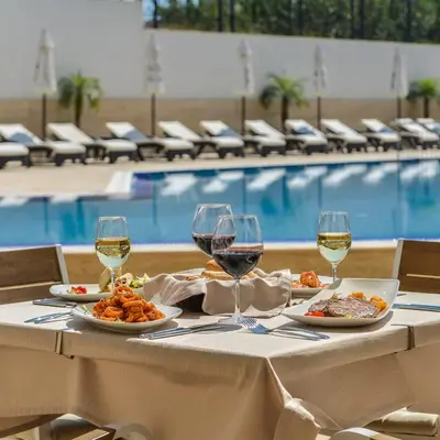 a table with plates of food and glasses of wine at FLORENCE SUITES APART HOTEL in Sveti Vlas