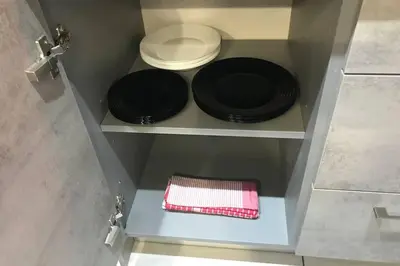 two black plates and a napkin on a shelf at Relax Apartment am Südstrand in Primorsko