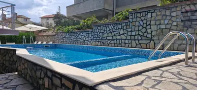 a swimming pool in a stone wall with a swimming pooliterator at Family hotel Favourite in Obzor