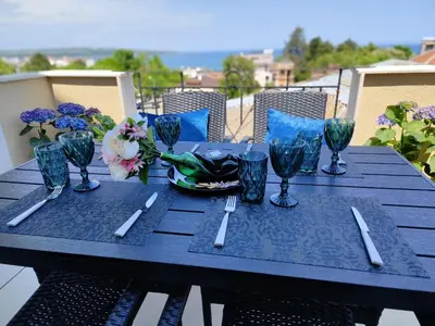 a blue table with glasses and a bowl of flowers at Аpartment Bella Vista in Obzor