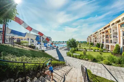 a couple of people walking down a walkway at a resort at Premier Fort Beach Luxury in Sveti Vlas