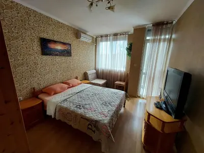a bedroom with a bed and a flat screen tv at Апартамент Кънтри-Лариса in Pomorie