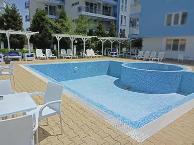 a large pool with chairs and tables and chairs at Апартамент Spirit in Nesebar