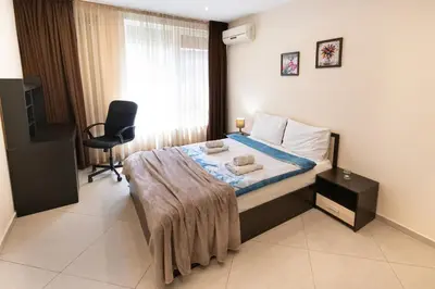a bedroom with a bed with a chair and a window at BeCentral! by RV Apartments in Varna City