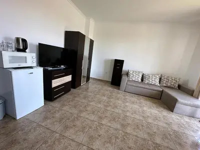 a living room with a couch and a tv at Вила Quiet Bay in Sozopol