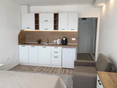 a kitchen with white cabinets and a sink and a couch at Студио Симона 2 - първа линия море in Lozenets