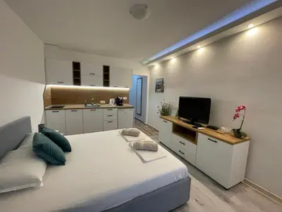 a bedroom with a bed and a kitchen with a television at Студио Симона 2 - първа линия море in Lozenets