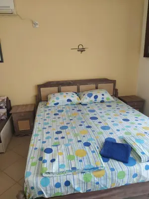 a bed with a blue comforter and pillows on it at Апартамент - студио в кв Сарафово с морски изглед in Burgas City