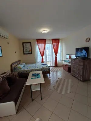 a living room with a couch and a tv at Апартамент - студио в кв Сарафово с морски изглед in Burgas City