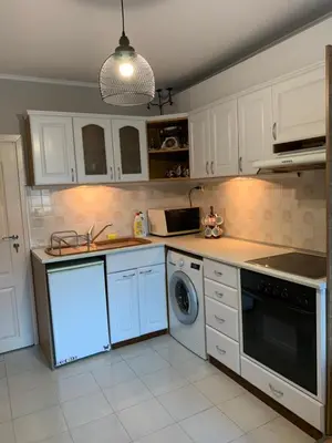 a kitchen with white cabinets and a washer and dryer at Анси in Pomorie