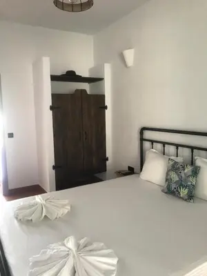 a bedroom with a bed with white sheets and a wooden door at Villa Oasis етаж1 in Lozenets