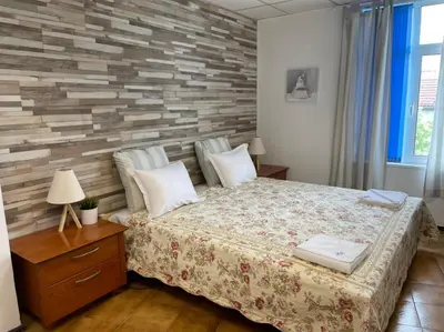 a bedroom with a bed and a brick wall at Апартамент Компас in Burgas City