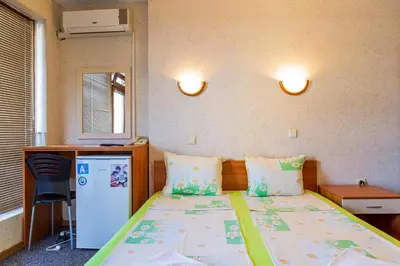 a small room with a bed and a refrigerator at Хотел Бриз in Kiten