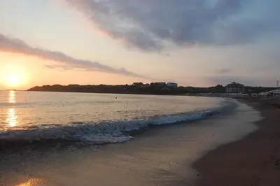 a beach with the sun setting in the water at Sea view apartment in Tsarevo