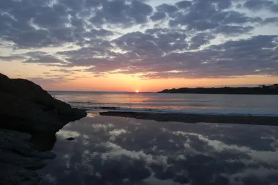 a sunset on the beach with a reflection in the water at Sea view apartment in Tsarevo