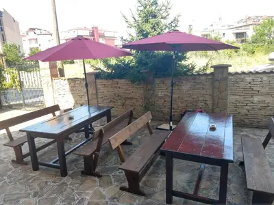 two picnic tables and umbrellas on a patio at Къща за гости Валена град Черноморец in Chernomorets