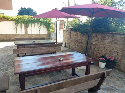 two benches and an umbrella on a patio at Къща за гости Валена град Черноморец in Chernomorets