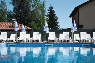 a group of chairs and umbrellas next to a swimming pool at Hotel Vanilla, Varna - Free parking in Varna City