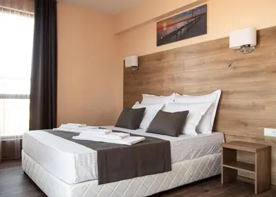 a bedroom with a large white bed with a wooden wall at Hotel Vanilla, Varna - Free parking in Varna City