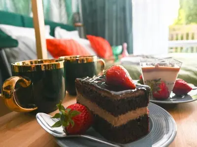 a piece of chocolate cake with strawberries on a table at Nessebar Fort Club - Prestige Apartments in Sunny Beach